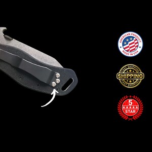 May include: Close-up of a black folding knife with a silver blade and a black pocket clip. The knife has a textured handle and is marked "AMERICAN PRODUCT MADE IN USA".