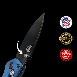 Puede incluir: Una navaja plegable negra con mango azul. La hoja es negra y presenta un logotipo de mariposa. La navaja est&aacute; etiquetada como "American Product Made in USA".