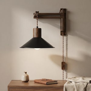 Op de afbeelding: Een wandlamp met een zwarte kap en houten accenten. De lamp is bevestigd aan een houten arm en heeft een rood-wit gestreept snoer. De lamp bevindt zich boven een houten kast.