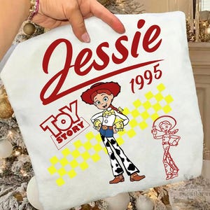 May include: White pillowcase featuring the name "Jessie" in red script above the year "1995". The pillowcase has a "Toy Story" logo and a cartoon image of Jessie the cowgirl. A smaller outline of Jessie is also on the pillowcase.