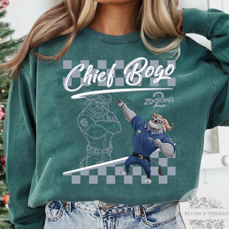 May include: Teal green sweatshirt featuring Chief Bogo from Zootopia. The design includes the text "Chief Bogo" above an illustration of the character in a police uniform. A second illustration of Chief Bogo is also present.