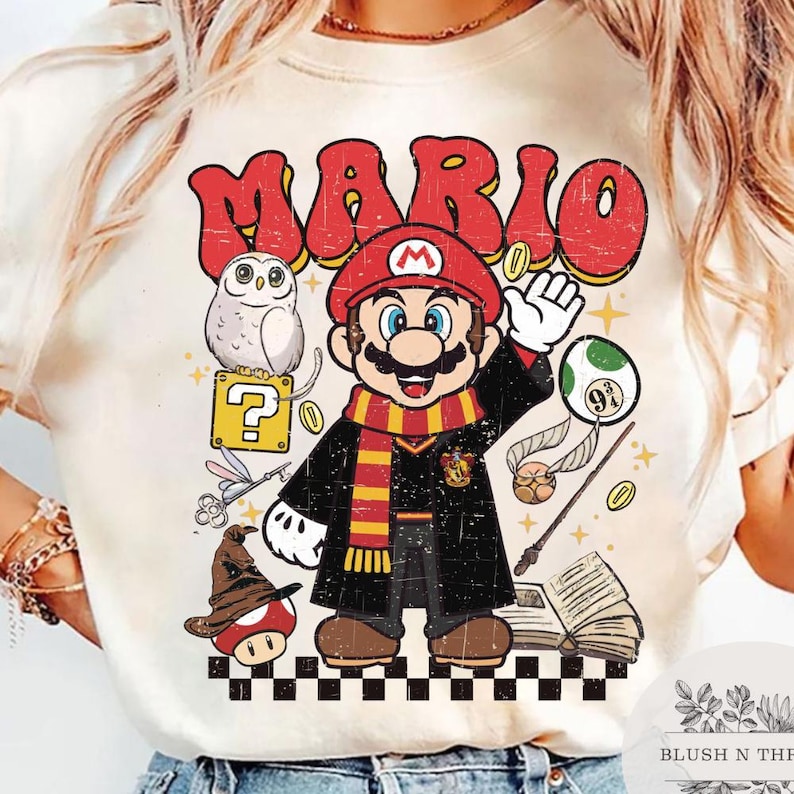 以下が含まれることがあります： クリーム色のTシャツ。赤い帽子とスカーフ、黒いローブを着たマリオのグラフィック。キャラクターの上には赤い文字で「MARIO」と書かれています。フクロウ、疑問符、キノコなどのグラフィックも含まれています。