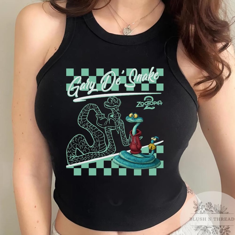 May include: Black tank top featuring a cartoon graphic of two snakes and a small character. The text "Gary De' Snake" is above the graphic, with "Zootopia 2" below. The design is set against a teal and white checkered background.