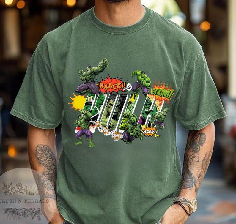 May include: Green t-shirt featuring a comic book style graphic of the Hulk. The design includes the word "Hulk" in a bold font, along with action words like "RAAACK!" and "BOOM!" and images of the Hulk in action.