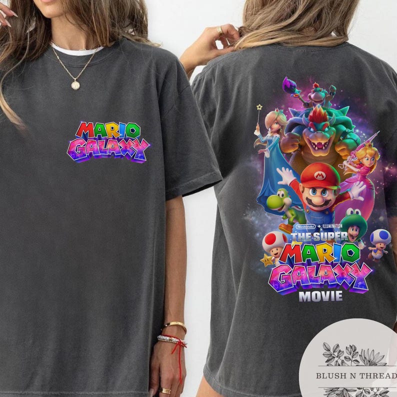 Puede incluir: Camiseta gris oscuro con el logo "Mario Galaxy" en la parte delantera y un gr&aacute;fico colorido de Mario y sus amigos en la parte trasera. La camiseta es de cuello redondo y manga corta.