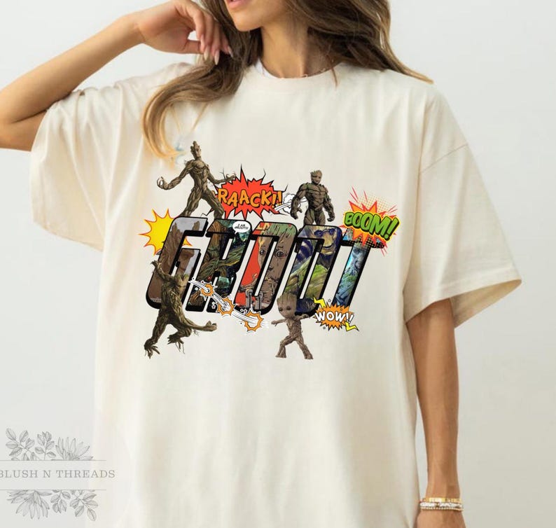 May include: Cream-colored t-shirt featuring a comic-style graphic of the character Groot from Guardians of the Galaxy. The design includes the word "GROOT" in bold letters, surrounded by action bubbles with phrases like "RAACK!" and "BOOM!"