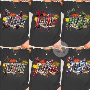 May include: Dark gray t-shirts featuring comic book characters and names. The shirts display the names "THOR", "DAD", "HULK", "GROOT", "IRON MAN", and "STEVE" in a bold, comic-style font, with action graphics and sound effects.