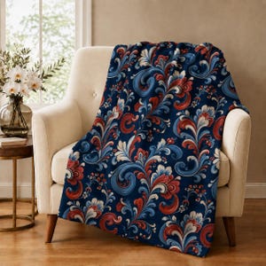 May include: A soft throw blanket featuring a dark navy blue background with a repeating pattern of swirling floral motifs in shades of red, white, and light blue. The design consists of intricate, curved leaf and petal shapes throughout.