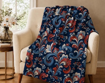 May include: A soft throw blanket featuring a dark navy blue background with a repeating pattern of swirling floral motifs in shades of red, white, and light blue. The design consists of intricate, curved leaf and petal shapes throughout.