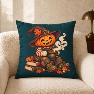 May include: A dark teal square throw pillow featuring a central illustration of a pumpkin-headed character wearing a purple witch hat and overalls, sitting on two books while stirring a small black cauldron with rising white steam and bats.