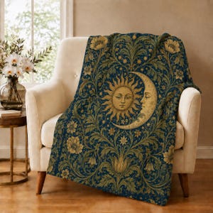 May include: A dark blue throw blanket featuring a repeating pattern of golden yellow suns and crescent moons surrounded by intricate floral and leafy botanical motifs. The design includes stylized flowers and vines in shades of gold and olive.