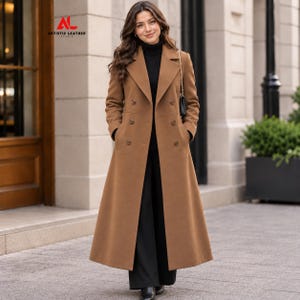 May include: A long, camel-colored double-breasted wool coat with notched lapels, six brown buttons, and two side pockets. The coat is worn over a black turtleneck sweater and black trousers. The logo ARTISTIC LEATHER STUDIO is visible.