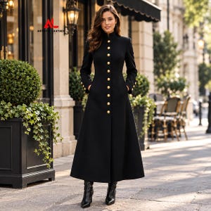 May include: A long black coat featuring a high collar, long sleeves, and a vertical row of gold-toned buttons down the front. The coat has a fitted bodice that flares toward the hem and includes side pockets. The text "AL ARTISTIC LEATHER" is visible.