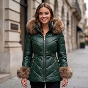 May include: A dark green quilted jacket featuring a full-length silver front zipper, a high collar, and a hood trimmed with thick brown faux fur. The sleeves are finished with matching brown faux fur cuffs, and the jacket has a fitted waist.