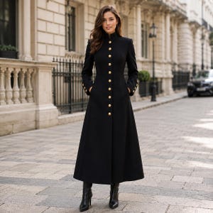 May include: A floor-length black coat featuring a high mandarin collar, long sleeves with buttoned cuffs, and a front vertical row of ten round gold-toned buttons. The garment is fitted through the bodice and flares slightly toward the hem.