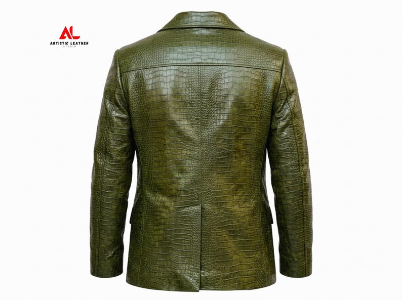 May include: An olive green blazer with a textured crocodile skin pattern. The back view shows a structured collar, long sleeves, and a single center vent at the hem. The logo ARTISTIC LEATHER STUDIO is printed in red and black in the upper left corner.