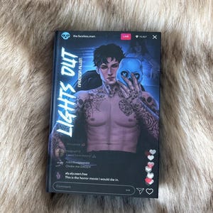 Peut inclure: Un livre de poche intitulé "LIGHTS OUT" par Navessa Allen. La couverture présente une personne tatouée tenant un masque de crâne bleu. Le livre a un design de style réseaux sociaux avec des commentaires et un indicateur en direct.
