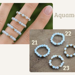 May include: Four rings made of light blue faceted beads and small metallic gold-tone spacer beads. The rings are labeled with the numbers 21, 22, 23, and 24. The text Aquamarin is visible in the upper right corner of the image display.