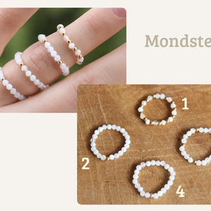 May include: Four rings made of small white beads and metallic gold or silver accents. The rings are labeled with numbers one through four, and the text Mondstein is displayed. The beads have a translucent appearance and are arranged in a circular band.