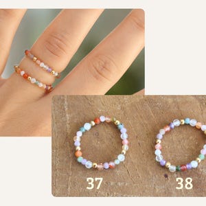 May include: Two elastic rings made of small, multicolored gemstone beads interspersed with tiny gold-toned metallic spheres. The rings are labeled 37 and 38, featuring a variety of pastel and vibrant stone colors arranged in a circular pattern.