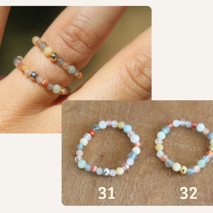 May include: Two elastic rings made of small, multicolored gemstone beads in shades of blue, orange, and white, accented with single metallic spheres. The rings are labeled 31 and 32, featuring a delicate, circular design with varied bead textures.