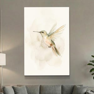 May include: Watercolor painting of a hummingbird in flight. The bird features soft green, beige, and peach tones, with outstretched wings. The background has a muted, watercolor wash effect, creating a serene and natural aesthetic.