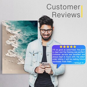 May include: A man wearing glasses and a denim jacket is smiling while looking at his phone. Behind him is a canvas print of an ocean wave in shades of blue and white. Text reads "Customer Reviews" and a customer review is visible.