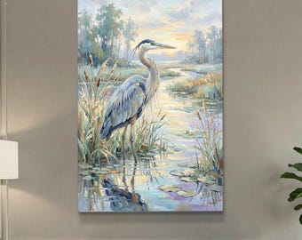 May include: A vertical wall art print featuring a blue heron standing in a marshy wetland. The scene includes tall reeds, lily pads, and calm water reflecting the soft light of a sunrise or sunset sky with muted blue, yellow, and green tones.