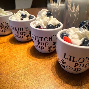 White Personalized Pup Cups with black letters filled with whipped cream and fruit