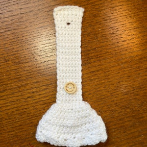 White crochet towel holder with wooden button open on a table