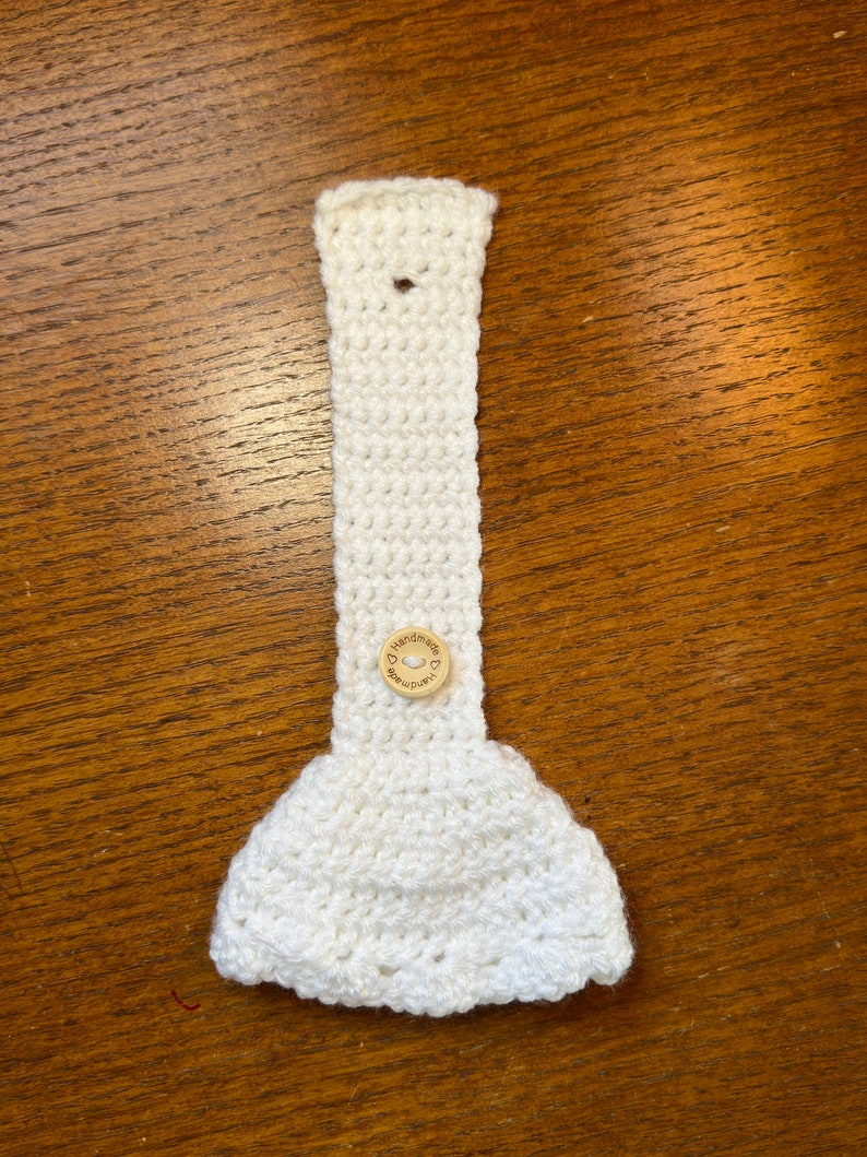 White crochet towel holder with wooden button open on a table