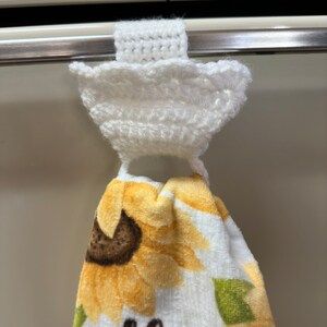 White crochet towel holder on an oven door holding a towel