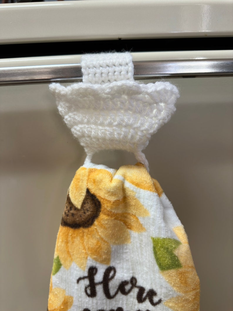 White crochet towel holder on an oven door holding a towel