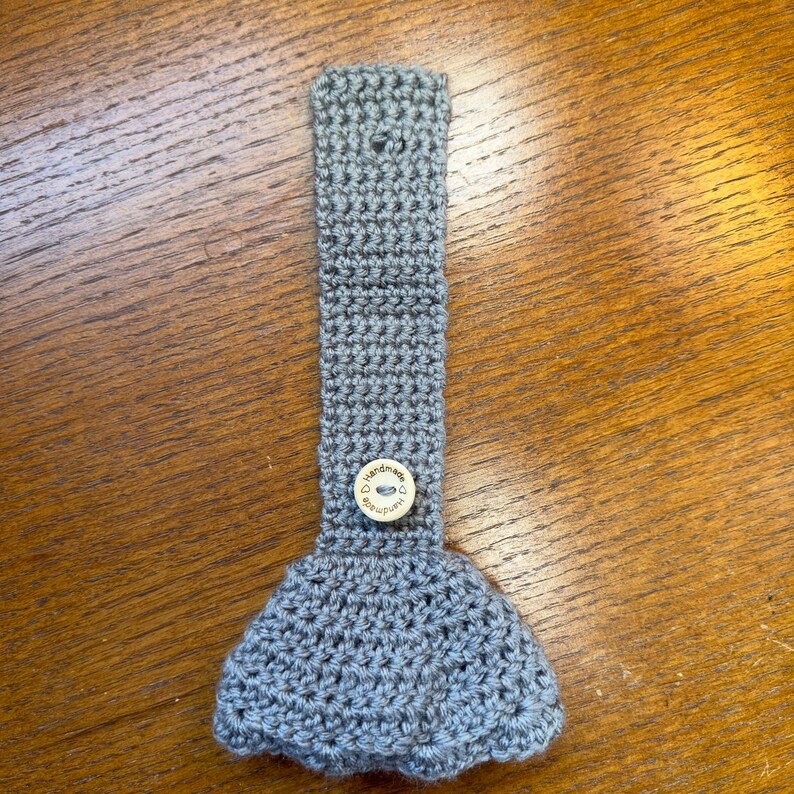 Gray crochet towel holder with wooden button on a wooden table