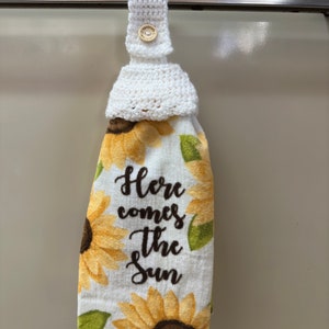 White crochet towel holder on an oven door holding a towel