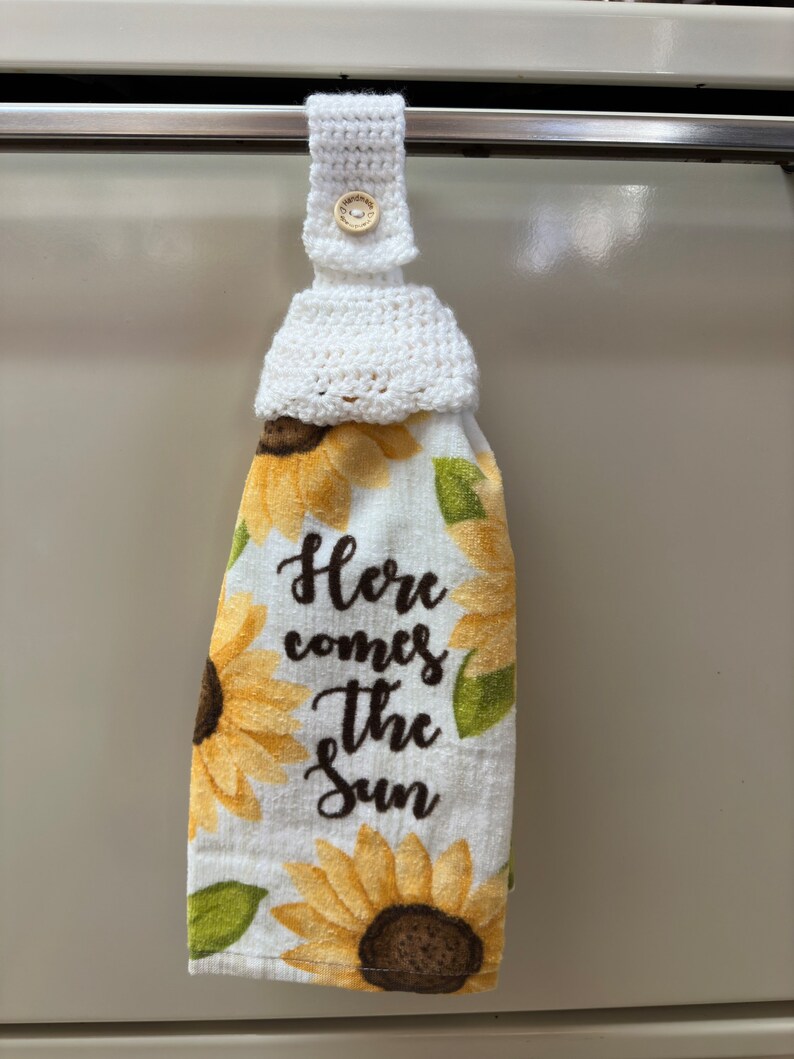 White crochet towel holder on an oven door holding a towel