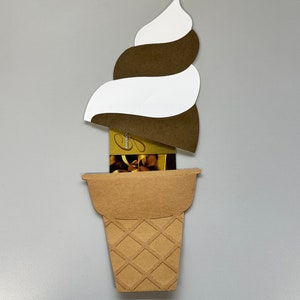 May include: A papercraft ice cream cone with a swirl of brown and white ice cream. The cone is made of brown paper with a waffle pattern. A gift card is visible inside the cone.