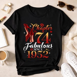 Puede incluir: Camiseta negra con un diseño brillante que celebra un 74 cumpleaños. El diseño incluye tacones rojos, las palabras "Chapter 74 Fabulous Since 1952" y una marca de beso de lápiz labial.