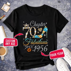 Puede incluir: Camiseta negra con un diseño de pedrería que celebra un 70 cumpleaños. El diseño incluye las palabras "Chapter 70 Fabulous Since 1956" y un zapato de tacón alto. La camiseta también tiene una corona y un beso.