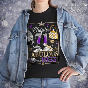 Puede incluir: Camiseta negra con un diseño gráfico para un 71 cumpleaños. El diseño incluye las palabras "Chapter 71 Fabulous Since 1955" con imágenes de tacones altos, un bolso y pintalabios. La camiseta está siendo usada.