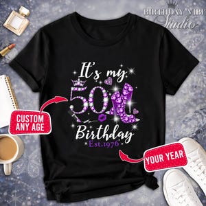 May include: Black t-shirt with a purple rhinestone design celebrating a 50th birthday. The design includes the text "It's my 50th Birthday" with a crown, high heels, and the year "Est. 1976."