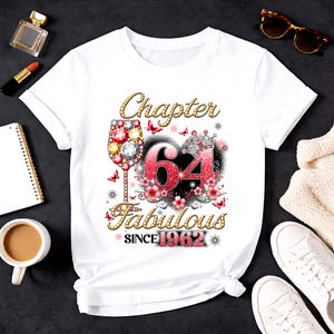 Puede incluir: Camiseta blanca con un diseño para un 64 cumpleaños. El diseño incluye las palabras "Chapter 64 Fabulous Since 1962", una copa de vino, flores y mariposas.