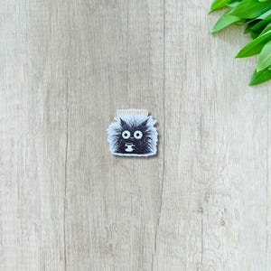 May include: A sticker featuring a cartoon black cat with large eyes, holding a coffee cup. The cat has fluffy fur and the word "DECAFFEINATED" is printed above it in orange.