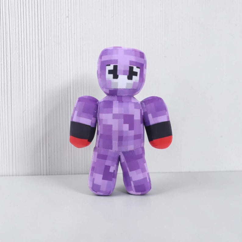 May include: A purple pixelated figure with a white face and black accents on the arms. The figure has red hands and is standing upright. The figure is a toy or collectible item.
