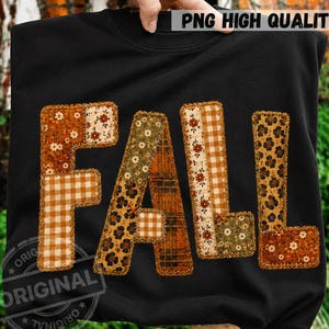 May include: A black sweatshirt featuring the word FALL in large block letters. Each letter is composed of various fabric patterns including orange floral prints, brown gingham, leopard spots, and plaid, all outlined with a decorative stitch.