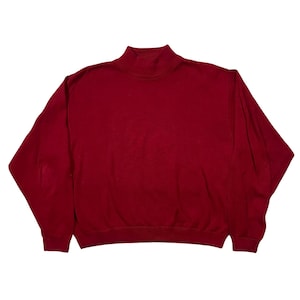 May include: A solid burgundy-colored sweatshirt with a mock neck collar. The long-sleeved top has a relaxed fit and ribbed cuffs. The garment is made of a soft material, perfect for casual wear.