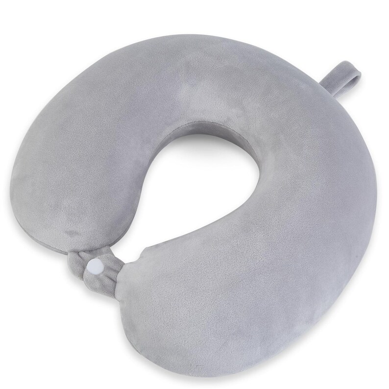 May include: A gray travel neck pillow with a U-shape design. The pillow has a soft, plush texture and a snap closure. A small loop is attached to the side. This travel pillow is designed for comfort and support during travel.