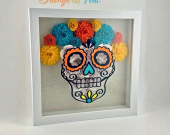 Könnte beinhalten: Ein gerahmtes Papierkunstwerk mit einem Sugar-Skull-Design. Der Totenkopf ist mit orangefarbenen, türkisfarbenen, gelben und roten Papierblumen verziert. Der Rahmen ist weiß, und der Text "Classic Orange & Teal" befindet sich oben.