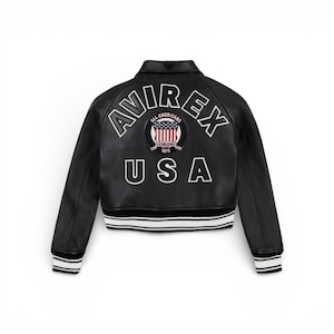 Puede incluir: Chaqueta de cuero negra con ribete a rayas blancas y negras en la cintura y los pu&ntilde;os. La parte trasera presenta el texto "AVIREX" sobre un parche circular con un dise&ntilde;o de bandera estadounidense y el texto "USA".