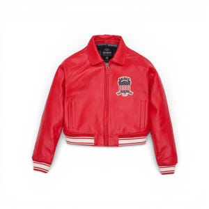 Puede incluir: Chaqueta de cuero roja brillante de estilo bomber. Presenta un dobladillo y pu&ntilde;os acanalados a rayas blancas y rojas. La chaqueta tiene una cremallera frontal y un peque&ntilde;o parche en el pecho con el texto "AVIREX".